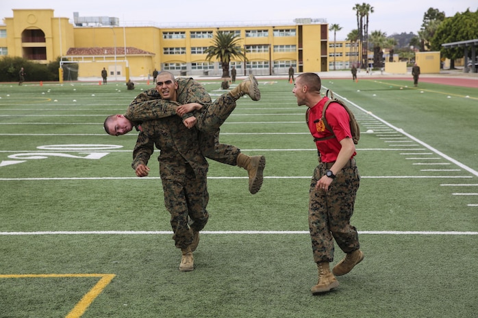 A recruit of Delta Company, 1st Recruit Training Battalion, conducts the fireman’s carry with a fellow recruit during the maneuver-under-fire portion of the Combat Fitness Test at Marine Corps Recruit Depot San Diego, March 10. The course for this portion covers 75 yards and requires recruits to perform exercises such as sprints, ammunition can carries, fireman’s carry and throwing a simulated grenade at a marked target. Recruits were timed as they ran through the course and needed to finish it in less than 2 minutes and 14 seconds for maximum points.  Annually, more than 17,000 males recruited from the Western Recruiting Region are trained at MCRD San Diego. Delta Company is scheduled to graduate April 1.