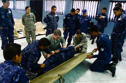 U.S. Air Force Senior Airman Jacob Radford and Staff Sgt. Karina Cortes, 628th Medical Operations Group medical technicians, show a group of Salvadoran air force members different techniques the USAF uses for loading patients onto a litter during a medical subject matter expert exchange at Ilopango Air Base, El Salvador, March 9, 2016. 12th Air Force (Air Forces Southern) surgeon general’s office, led a five-member team of medics from around the U.S. Air Force on a week-long medical subject matter expert exchange in El Salvador. (U.S. Air Force photo by Tech. Sgt. Heather R. Redman)