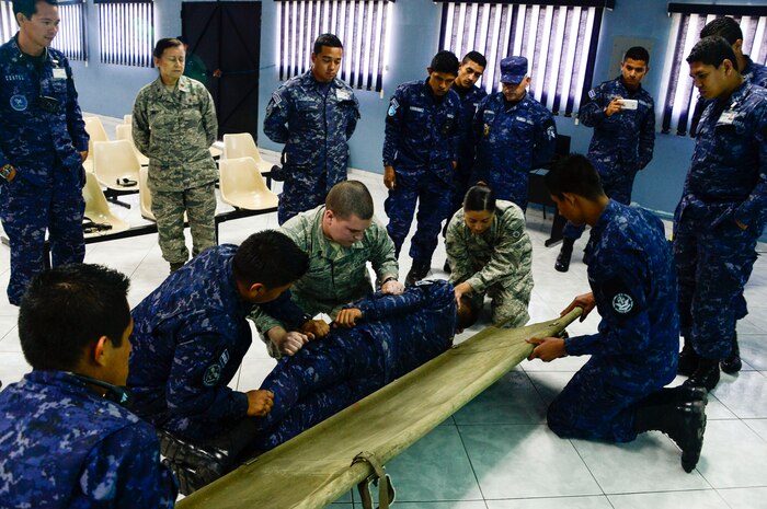 U.S. Air Force Senior Airman Jacob Radford and Staff Sgt. Karina Cortes, 628th Medical Operations Group medical technicians, show a group of Salvadoran air force members different techniques the USAF uses for loading patients onto a litter during a medical subject matter expert exchange at Ilopango Air Base, El Salvador, March 9, 2016. 12th Air Force (Air Forces Southern) surgeon general’s office, led a five-member team of medics from around the U.S. Air Force on a week-long medical subject matter expert exchange in El Salvador. (U.S. Air Force photo by Tech. Sgt. Heather R. Redman)