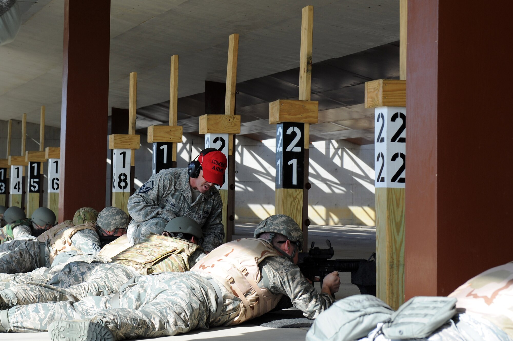 U.S. Air Force Master Sgt. Ryan Mclain, the noncommissioned officer in charge of combat arms training and maintenance assigned to the 633rd Security Forces Squadron, assists an Airman during qualifications on the M-4 Carbine at Langley Air Force Base, Va., March 8, 2016. Airmen shoot from different positions as well as with their gas mask on in order to successfully demonstrate the necessary requirements. (U.S. Air Force photo by Senior Airman Brittany E. N. Murphy)