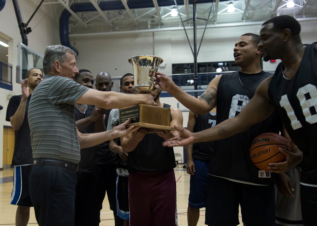 John Hickok, the fitness director assigned to the 633rd Force Support Squadron, presents the Joint Base Langley-Eustis all-star basketball game trophy to the Fort Eustis All-Stars at Langley Air Force Base, Va., March 9, 2016. The Fort Eustis team defeated the Langley All-Stars with a score of 64 to 53. (U.S. Air Force photo by Staff Sgt. J.D. Strong II)