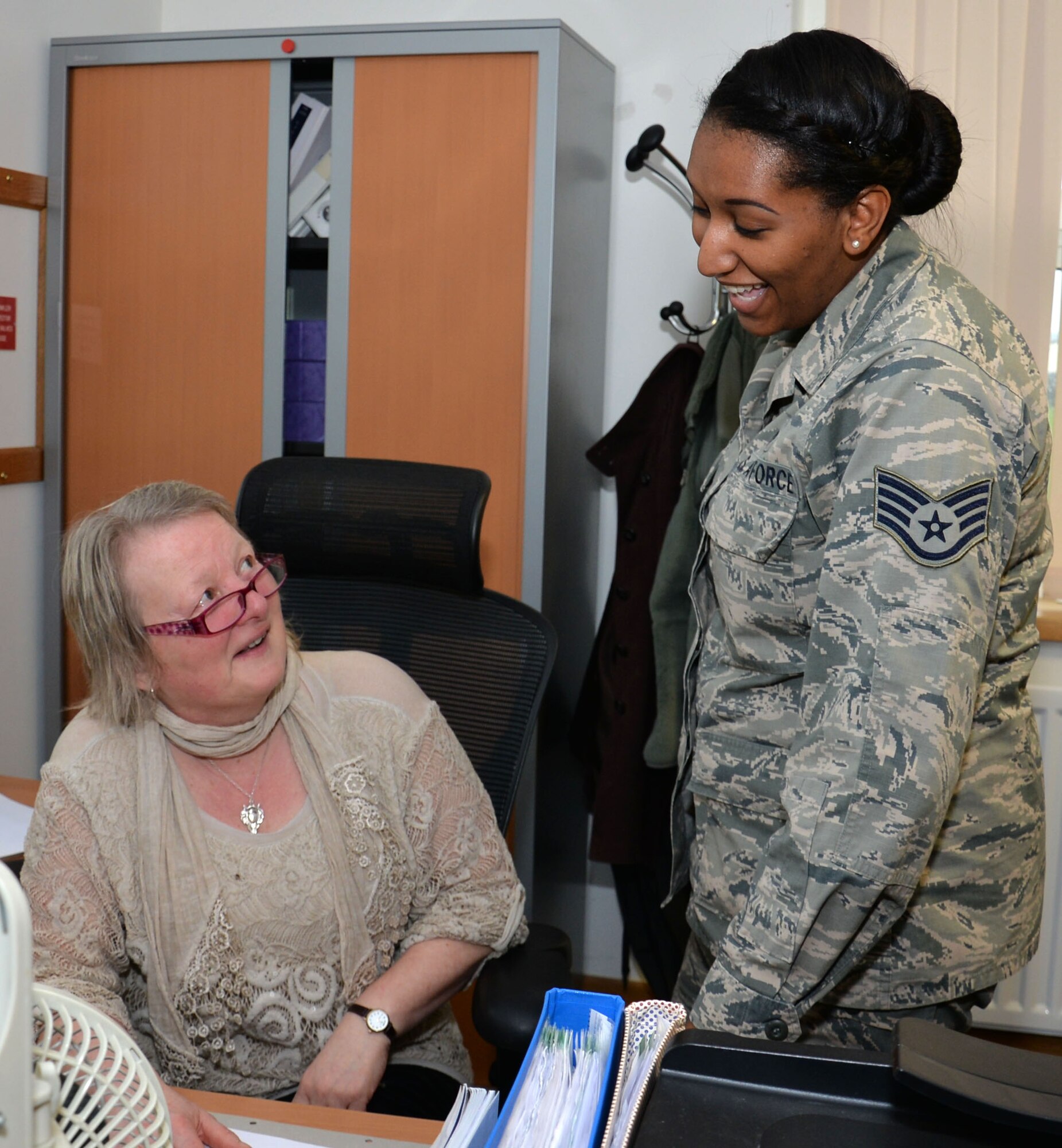 U.S. Air Force Staff Sgt. Diamond Wilkins, right, 100th Civil Engineer Squadron requirements and optimization section craftsman, speaks with Anne Edward, contractor help desk employee, about a scheduled project March 9, 2016, on RAF Mildenhall, England. Sometime in the near future their system is going to change, and with that will come a lot of changes to their facility manager program and how they input work requests. (U.S. Air Force photo by Gina Randall/Released)