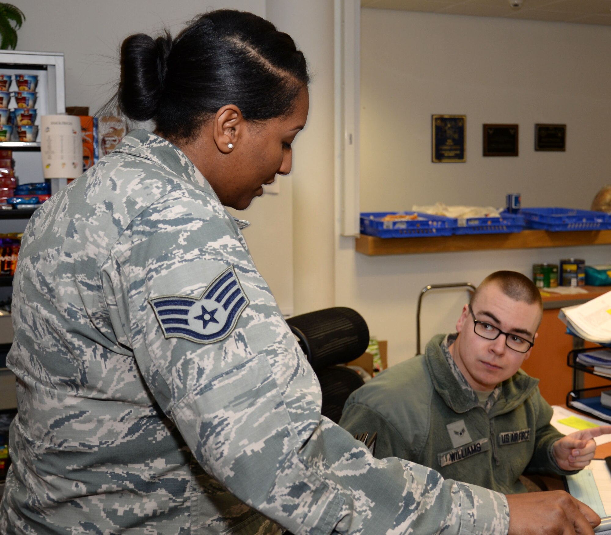 U.S. Air Force Staff Sgt. Diamond Wilkins, left, 100th Civil Engineer Squadron requirements and optimization section craftsman, speaks to U.S. Air Force Airman 1st Class Martin Williams, 100th CES Service Call Desk operations manager apprentice, about an upcoming project March 9, 2016, on RAF Mildenhall, England. Wilkins and her team have many duties including running the construction program, taking care of facility managers and scheduling power outages. (U.S. Air Force photo by Gina Randall/Released)