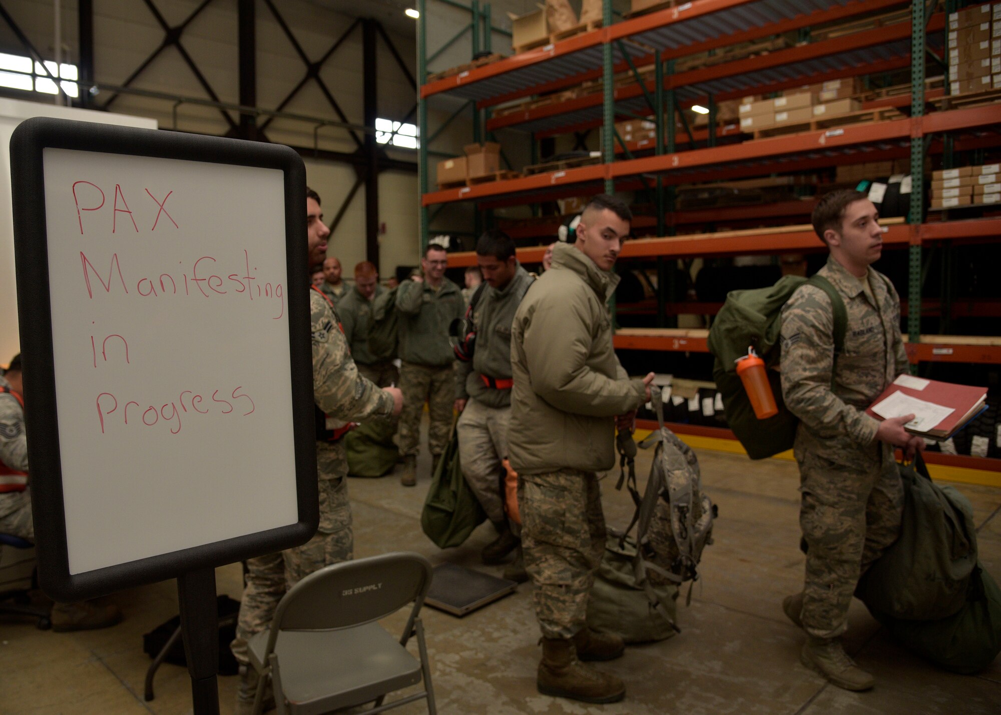U.S. Air Force Airmen wait in line to weigh their gear at Misawa Air Base, Japan, March 15, 2016. After Airmen were cleared through the Personnel Deployment Function line, they receive additional gear from individual protective equipment, and then were weighed by manifest Airmen. This calculates how much weight is going on to the aircraft before they deploy. (U.S. Air Force photo by Senior Airman Deana Heitzman)