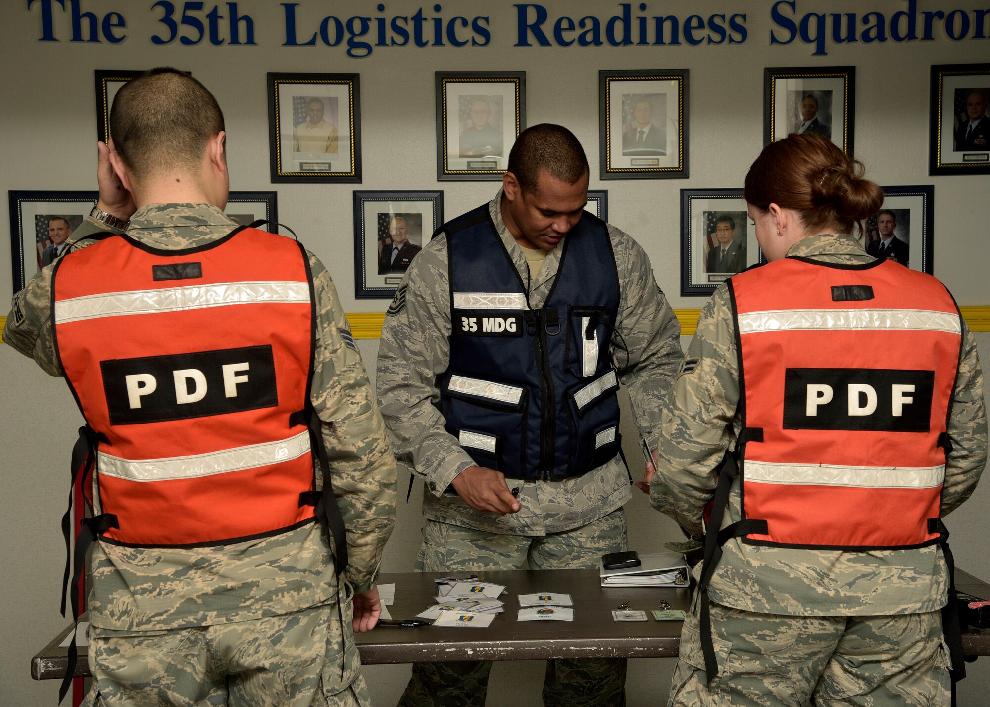 U.S. Air Force Senior Airman Robbie Day, left, and Airman 1st Class Danielle Streeter, right, fitness specialists with the 35th Force Support Squadron, check Tech. Sgt. Anthony Nelson, center, a public health technician with the 35th Medical Group, into the mock Personnel Deployment Function at Misawa Air Base, Japan, March 15, 2016. Day and Streeter performed security duties ensuring the PDF was safe and secure for Team Misawa personnel. The PDF kicked-off Beverly Sunrise 16-03, an operational readiness exercise testing Misawa’s mission capabilities. (U.S. Air Force photo by Senior Airman Deana Heitzman)