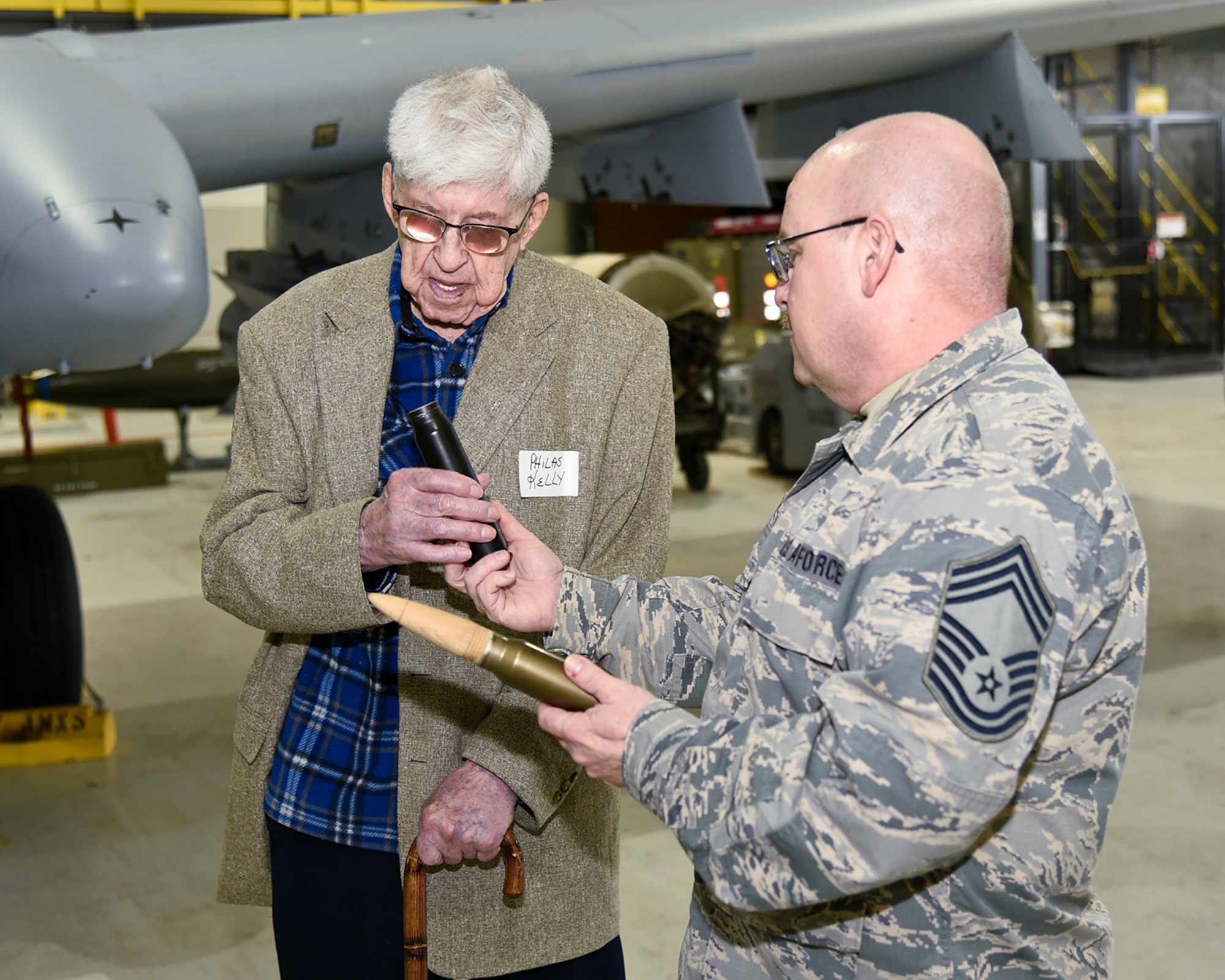 Chief Master Sgt. David Myers of the 127th Aircraft Maintenance Squadron shows a dummy 30mm round to Philas Kelly, who, at age 102, is likely the oldest living member of the 107th Observation Squadron of the Michigan National Guard. Myers and his team of maintenance Airmen support the current 107th Fighter Squadron, which flies the A-10 Thunderbolt II aircraft. Kelly visited his old unit at Selfridge Air National Guard Base, Mich., on March 15, 2016. (U.S. Air National Guard photo by Terry Atwell)