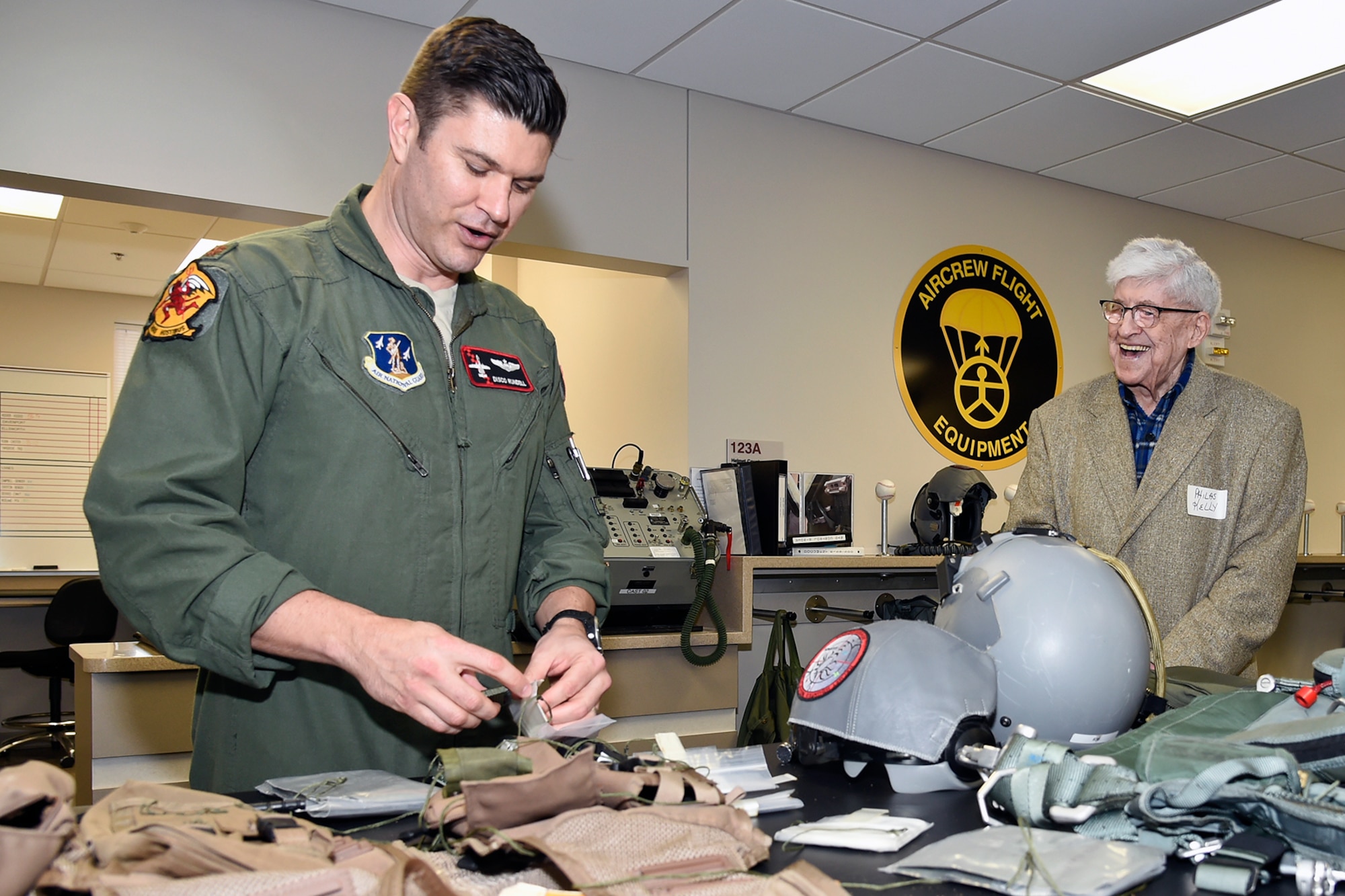 Major Bill Rundell, a pilot with the 107th Fighter Squadron, shows some of the life support equipment used by Air Force pilots to Philas Kelly, who served in the 107th prior to World War II, during a visit by Kelly to the squadron at Selfridge Air National Guard Base, March 15, 2016. (U.S. Air National Guard photo by Terry Atwell)