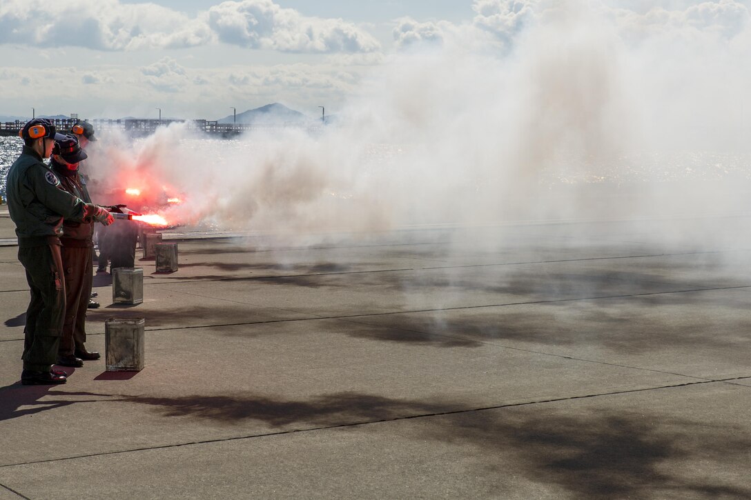 Japan Maritime Self-Defense Force aviators ignite nighttime smoke signals during Winter Survival Training at Marine Corps Air Station Iwakuni, Japan, March 9-11, 2016. Mandatory for all aviators and aircrew, the JMSDF conducts this training semi-annually, once in the summer and once in the winter. The aviators set off two smoke signals: red smoke for daytime and gray smoke with a red flashing light for nighttime. (U.S. Marine Corps photo by Lance Cpl. Aaron Henson/Released)