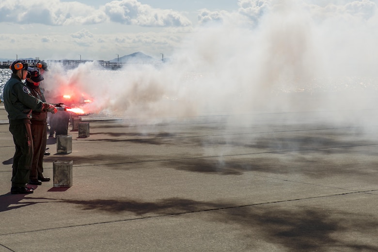 Japan Maritime Self-Defense Force aviators ignite nighttime smoke signals during Winter Survival Training at Marine Corps Air Station Iwakuni, Japan, March 9-11, 2016. Mandatory for all aviators and aircrew, the JMSDF conducts this training semi-annually, once in the summer and once in the winter. The aviators set off two smoke signals: red smoke for daytime and gray smoke with a red flashing light for nighttime. (U.S. Marine Corps photo by Lance Cpl. Aaron Henson/Released)