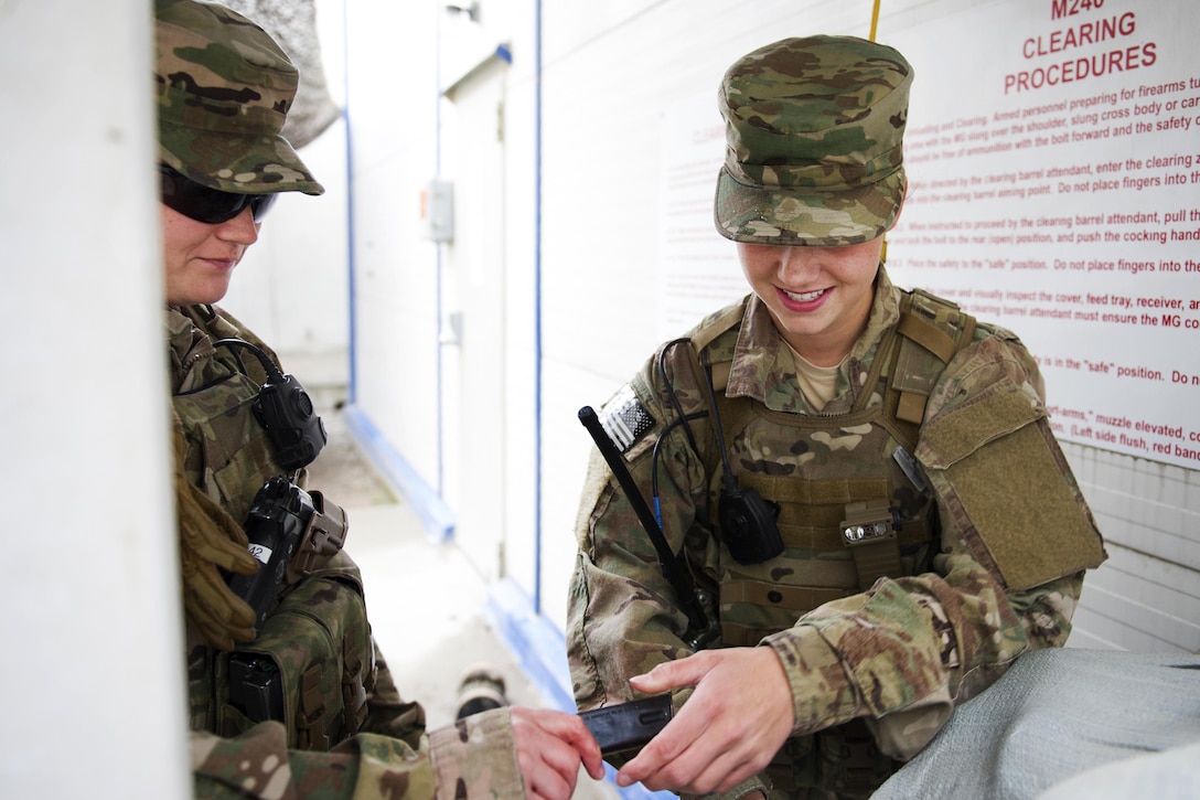 Air Force Senior Airman Bre Balk, left, supervises Airman 1st Class Alexandra Powell at a clearing barrel as she loads an M9 pistol on Bagram Airfield, Afghanistan, March 16, 2016, before a mission to Camp Shorabak, Afghanistan. Balk and Powell are security members assigned to the 455th Expeditionary Security Forces Squadron Fly-Away Security Team. The team provides ground safety and cockpit denial to protect the aircraft and crew. Air Force photo by Tech. Sgt. Robert Cloys