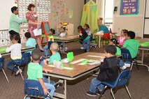 Martha Cook, HNC executive officer, and Stephanie Caldwell, EEO specialist, talk to pre-kindergarten students about their group project during the First Baptist Child Development Center & Academy science fair.
