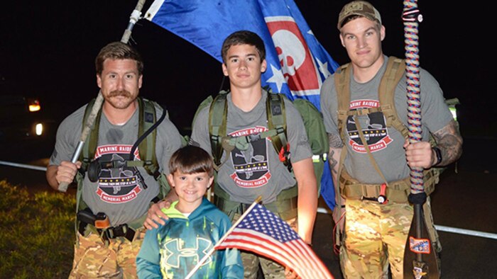 Two Marines greet a little boy with an American flag on the march route of a 770-mile ruck from Navarre, Florida, to Marine Corps Base Camp Lejeune, North Carolina. The ruck is in honor of 11 service members who died in a helicopter crash one year ago.