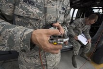 U.S. Air Force Staff Sgt. Joshua Jaynes, 41st Helicopter Maintenance Unit crew chief craftsman, examines a rescue hoist clip while Senior Airman John Dwinell, 41st HMU crew chief journeyman, annotates the repairs done to an HH-60G Pave Hawk helicopter after routine maintenance, March 16, 2016, at Moody Air Force Base, Ga. The clip is attached to the end of a 200-foot cable and latches onto pararescuemen during combat search and rescue missions. (U.S. Air Force Photo by Airman 1st Class Janiqua P. Robinson/Released)