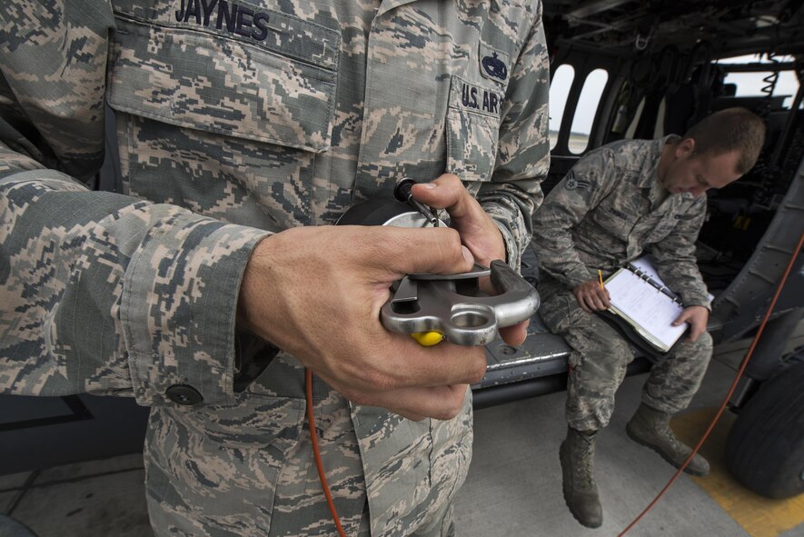 U.S. Air Force Staff Sgt. Joshua Jaynes, 41st Helicopter Maintenance Unit crew chief craftsman, examines a rescue hoist clip while Senior Airman John Dwinell, 41st HMU crew chief journeyman, annotates the repairs done to an HH-60G Pave Hawk helicopter after routine maintenance, March 16, 2016, at Moody Air Force Base, Ga. The clip is attached to the end of a 200-foot cable and latches onto pararescuemen during combat search and rescue missions. (U.S. Air Force Photo by Airman 1st Class Janiqua P. Robinson/Released)