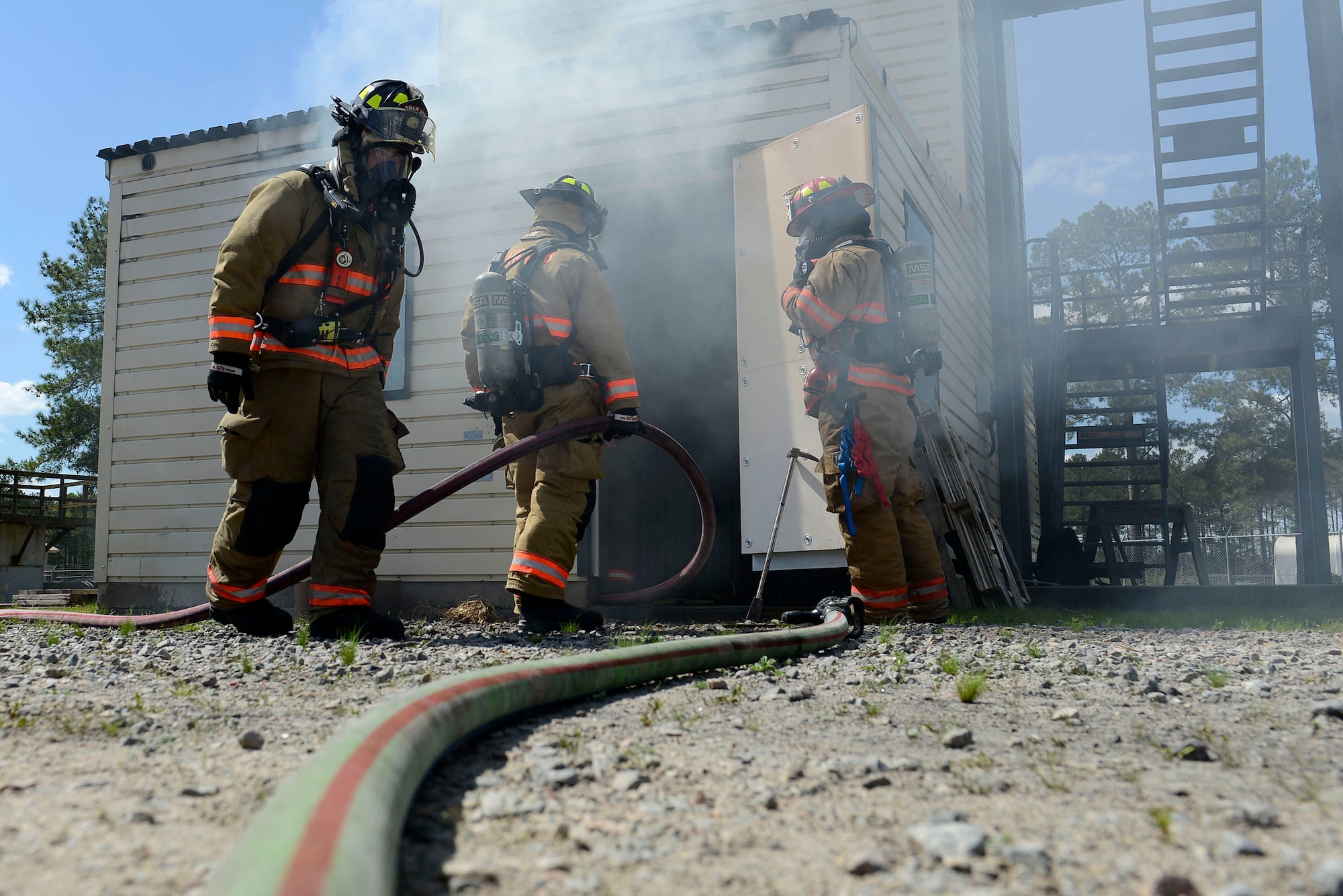 U.S. Airmen assigned to the 20th Civil Engineer Squadron fire department prepare to clear smoke from a training burn house at Shaw Air Force Base, S.C., March 14, 2016. Airmen assigned to the 20th CES utilize the burn house to practice procedures for extracting victims in a building fire scenario. (U.S. Air Force photo by Airman 1st Class Christopher Maldonado)