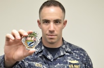 Lieutenant Nick Bona presents the 116th Pacific Fleet Submarine Force birthday ball’s challenge coin. The ball celebrates 116 years of distinguished service by the submarine force. (U.S. Navy photo by Lieutenant Junior Grade Samuel Boyle/Released)
