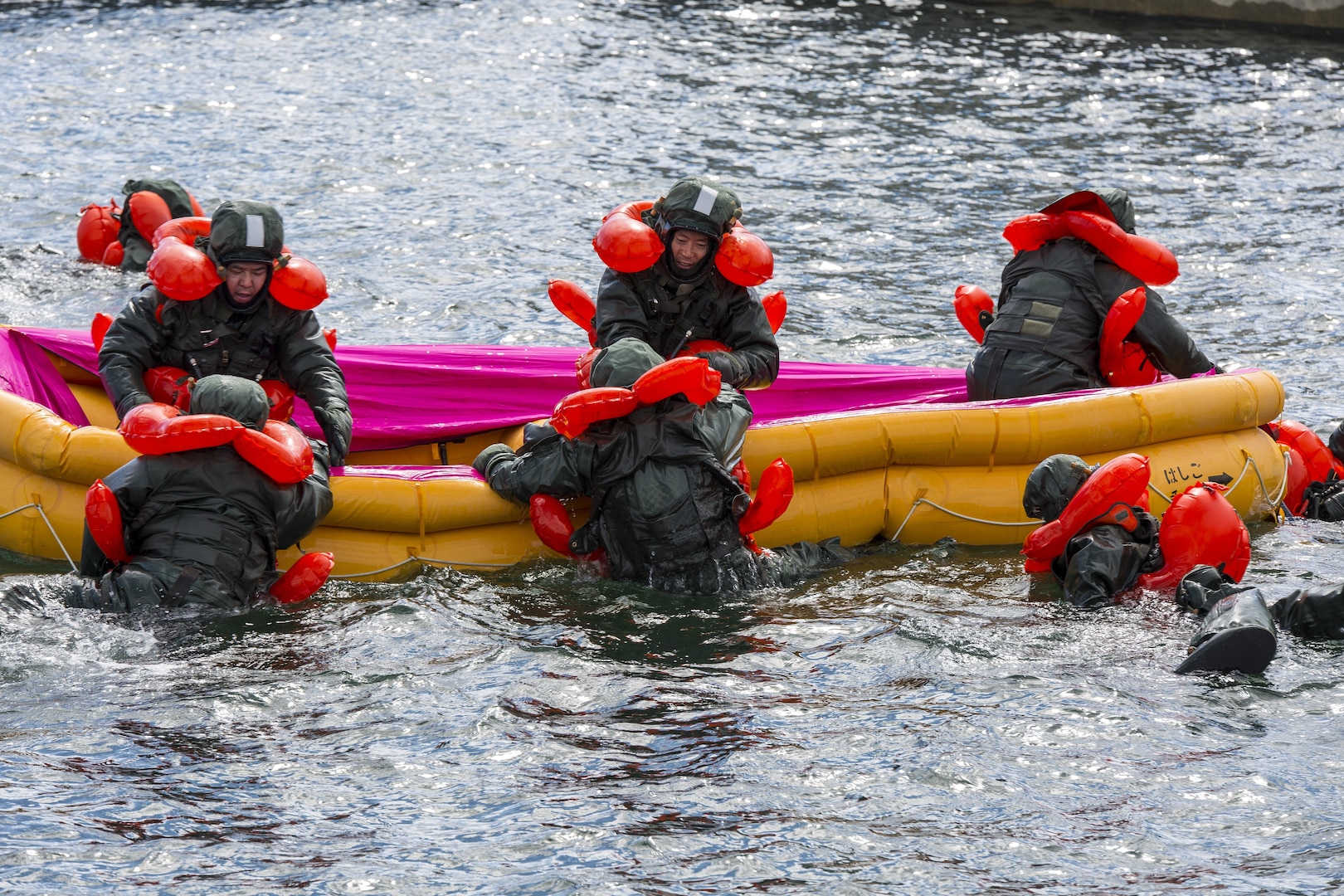 Japan Maritime Self-Defense Force aviators assist each other in boarding an inflatable raft during Winter Survival Training at Marine Corps Air Station Iwakuni, Japan, March 9-11, 2016. Mandatory for all aviators and aircrew, the JMSDF conducts this training semi-annually, once in the summer and once in the winter. The final portion consisted of drifting training where the aviators dressed in Taikan Taisui Fuku, a cold and water resistant suit. They jumped into the water, swam to inflatable-life-saving boats and worked as a team to climb aboard. (U.S. Marine Corps photo by Lance Cpl. Aaron Henson/Released)