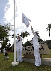 160311-N-QL961-141 PEARL HARBOR (Mar. 11, 2016) Culinary Specialist 2nd Class David Johnson, left, and Operations Specialist 3rd Class Jasmine Bencid, both members of the Joint Base Pearl Harbor-Hickam (JBPHH) color guard, raise the USS Nevada (BB 36) battleship flag during a commemoration ceremony for the ship's 100th anniversary of its commissioning at the USS Nevada memorial on JBPHH. The ceremony was conducted at the Nevada memorial simultaneously as a similar ceremony was being held in Carson City, Nevada. (U.S. Navy photo by Mass Communication Specialist 1st Class Phillip Pavlovich/Released)