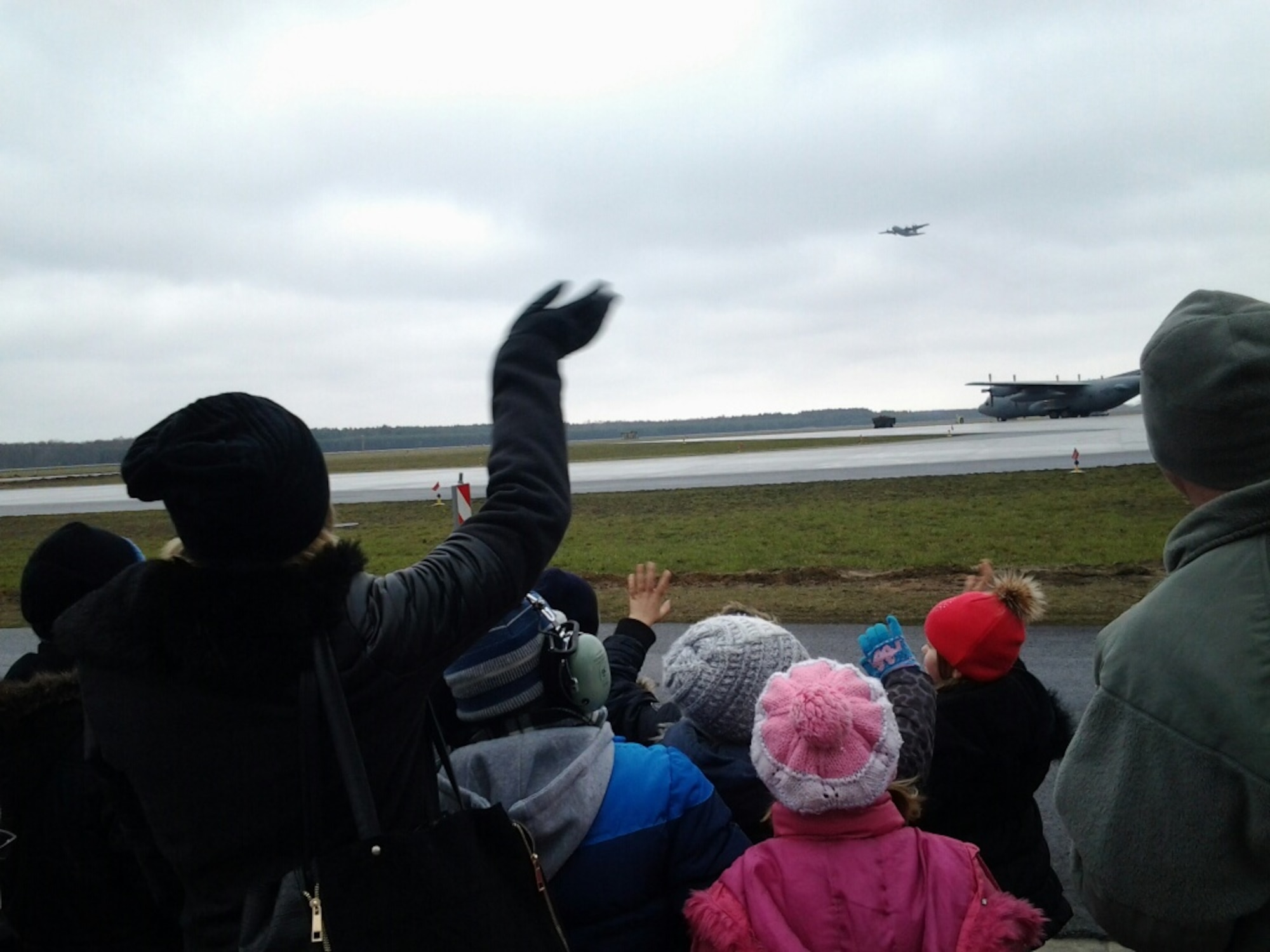 Children from a local orphanage wave as they watch a C-130 take off from Powitz Air Base, Poland March 15. (Air Force Photo/Chief Master Sgt. Joe Bystedt)