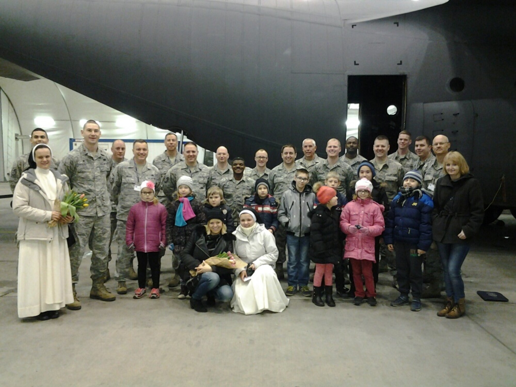 934th members pose with visitors from a local orphanage in front of a Polish C-130 at Powitz Air Base, Poland March 15. (Air Force Photo/Chief Master Sgt. Joe Bystedt)