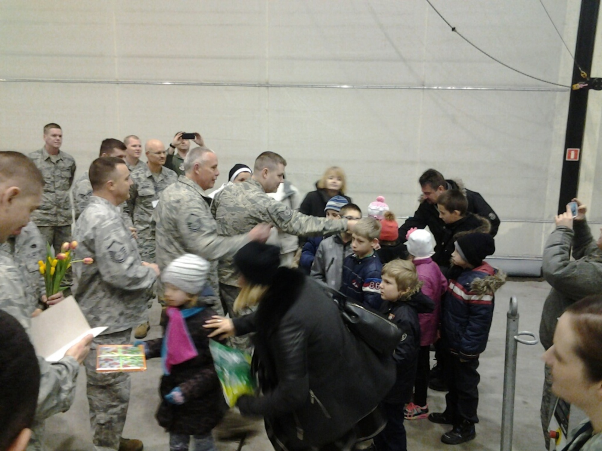 From left, Master Sgts. Chuck Keller, Jeff Tomkins, and Tech. Sgt. Shane Graham, 934th Maintenance Squadron, welcome children from a local orphanage to Powitz Air Base, Poland March 15. (Air Force Photo/Chief Master Sgt. Joe Bystedt)

