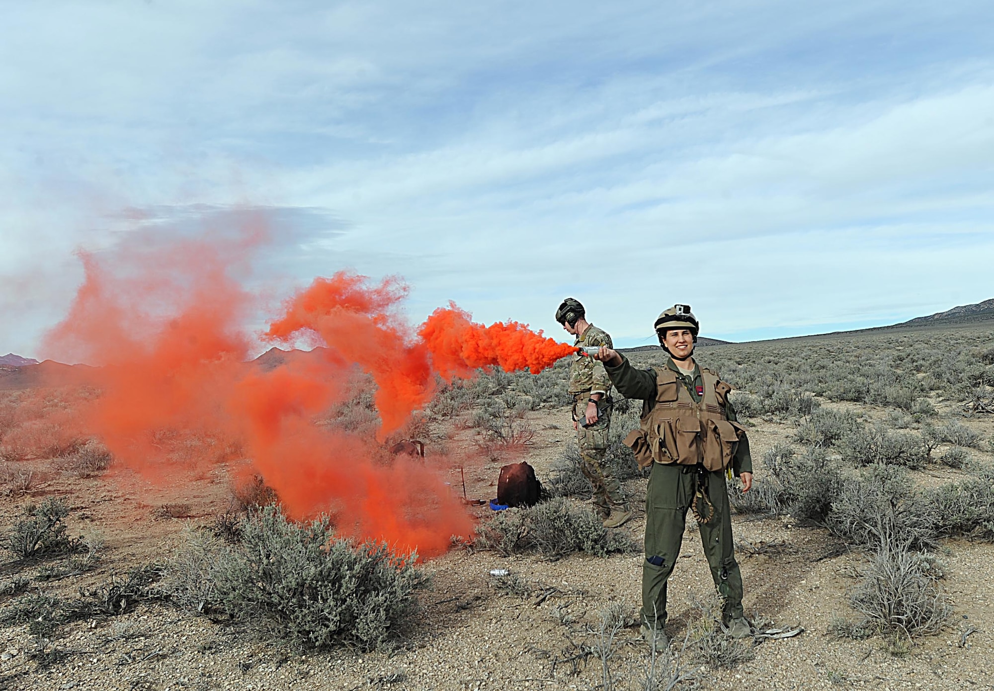 First Lt. Adria Trgovcich, 350th Air Refueling Squadron navigator, uses a signal smoke flare, March 9, 2016, near Rachel, Nev. The flare signaled her location to the search helicopter trying to locate her and her missing navigator during Red Flag 16-2 personnel recovery exercise. (U.S. Air Force photo/Senior Airman David Bernal Del Agua)