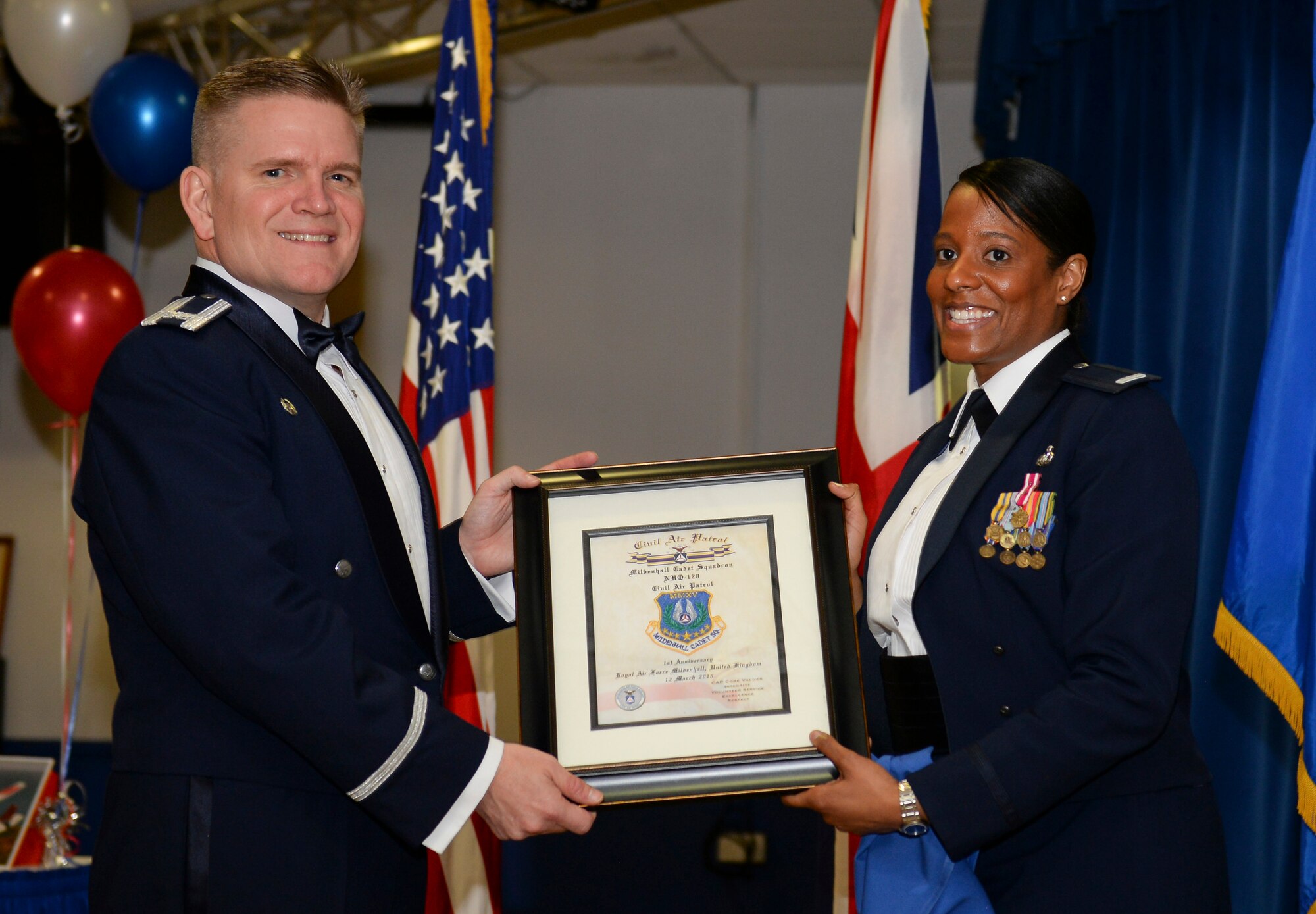 U.S. Air Force Senior Master Sgt. Sharreen Taylor, right, 100th Operations Support Squadron host aviation resource management superintendent and Mildenhall Cadet Squadron commander, presents Col. Thomas D. Torkelson, 100th Air Refueling Wing commander, with a framed unit patch during the CAP dining out March 12, 2016, at the Liberty Club on RAF Lakenheath, England. The Civil Air Patrol performs three missions: emergency services, cadet programs and aerospace education. The main mission of RAF Mildenhall’s CAP squadron is to conduct the cadet program, which provides training for cadets consisting of leadership, aerospace education and physical fitness. (U.S. Air Force photo by Staff Sgt. Micaiah Anthony/Released)