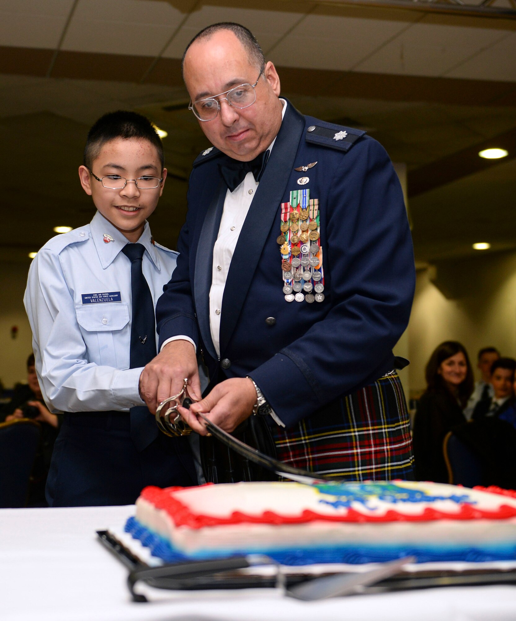 Civil Air Patrol Lt. Col. Darren Cruz, Mildenhall Cadet Squadron aerospace education officer, and a CAP cadet cut a cake during the CAP dining out March 12, 2016, at the Liberty Club on RAF Lakenheath, England. The Mildenhall Cadet Squadron celebrated its first year with a dining out since the unit’s activation March 2, 2015. The cadet program and aerospace education opportunities are available to all U.S. Military and Department of Defense dependents from ages 12 to 18 in the Mildenhall, Lakenheath and Feltwell communities. (U.S. Air Force photo by Staff Sgt. Micaiah Anthony/Released)