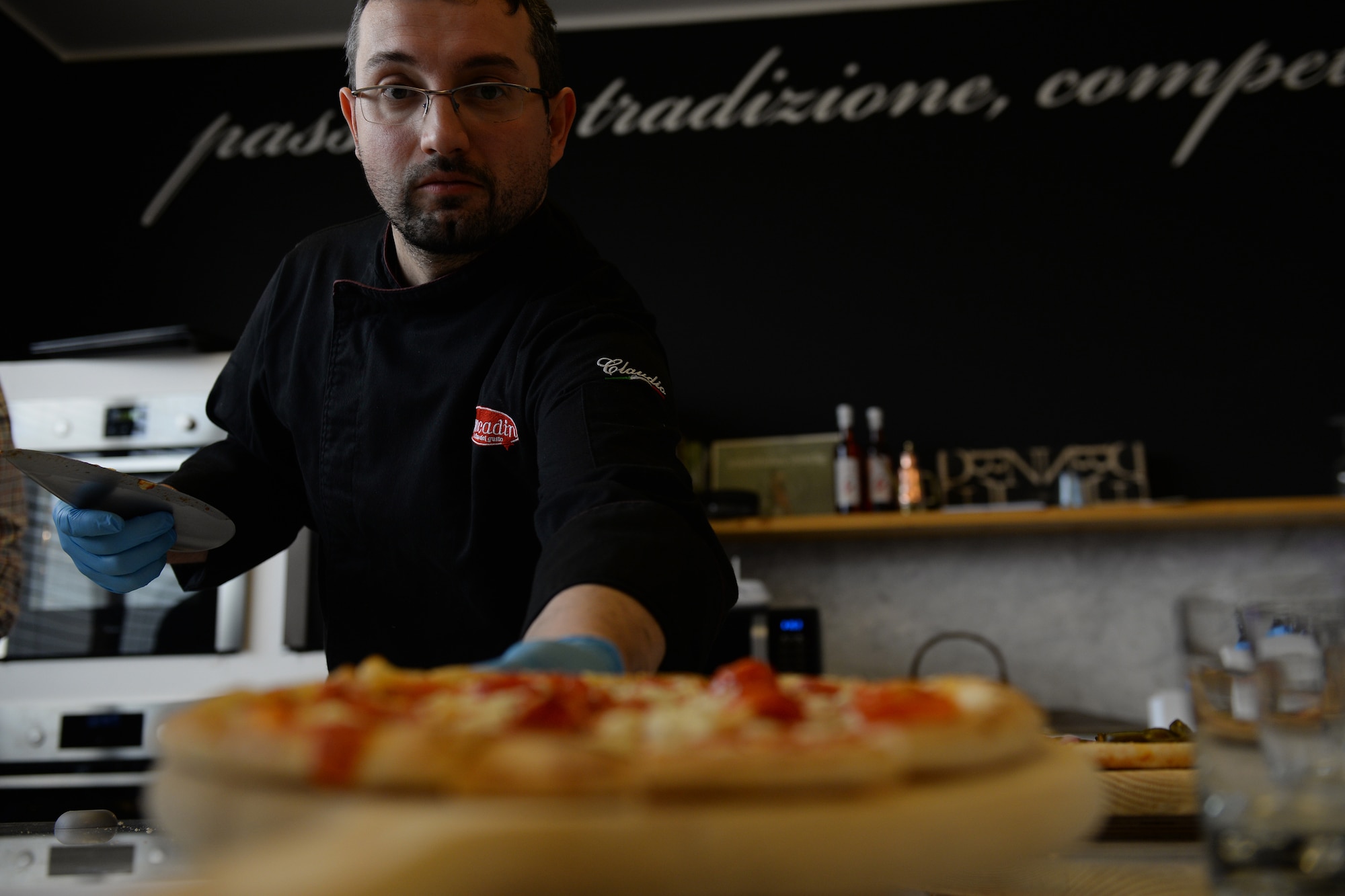 Claudio Gaspardo slices and serves pizza during a local pizza factory tour, March 14, 2016, in Meduno, Italy. Officers from the 31st Logistics Readiness Squadron visited a local business to understand how it overcame obstacles to be successful. (U.S. Air Force photo by Airman 1st Class Cary Smith/Released) 