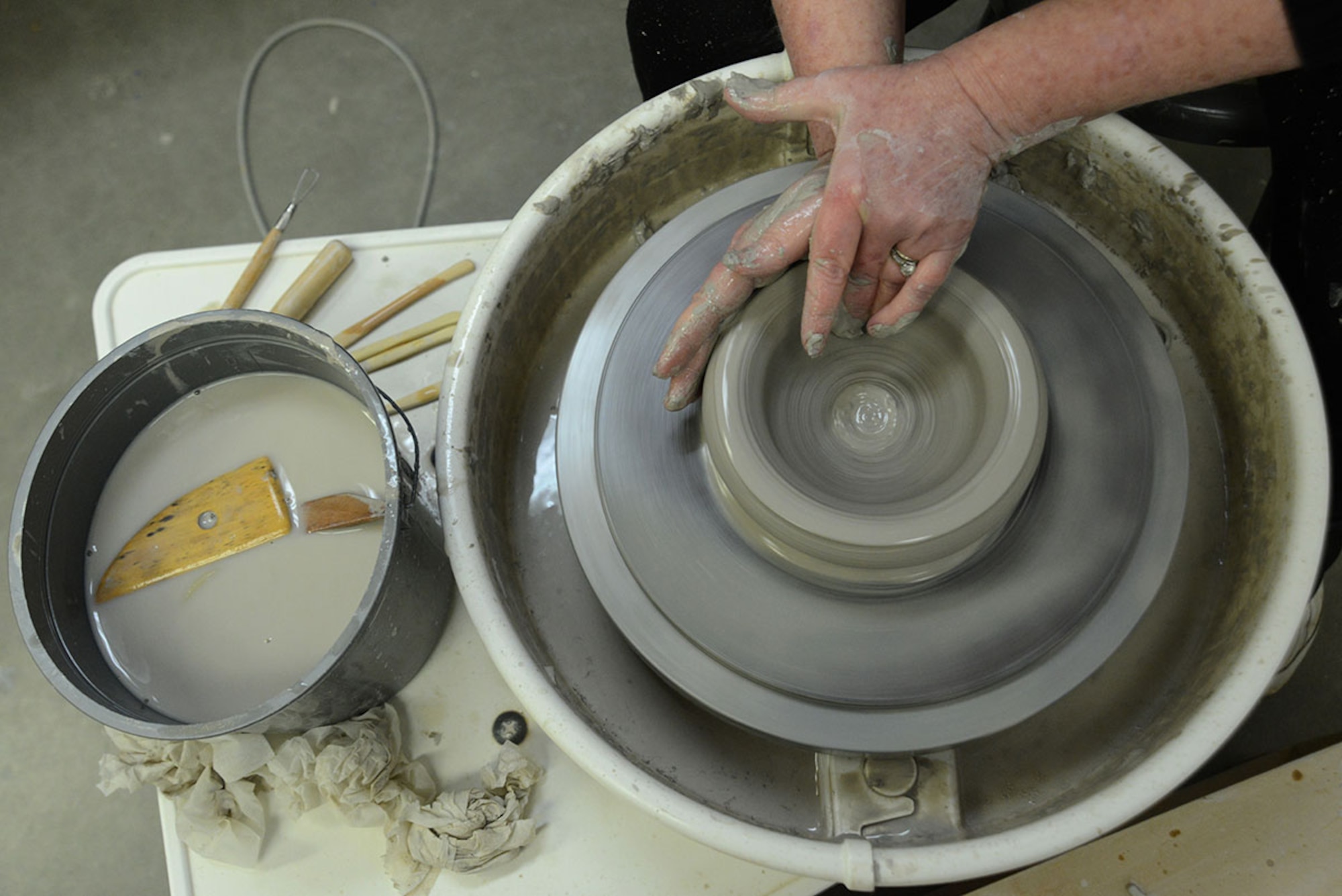 U.S. Coast Guard spouse Laura Fox molds a bowl with her fingers on a pottery wheel at the Polar Express Arts and Crafts Center at Joint Base Elmendorf-Richardson, Alaska, Feb. 28, 2016. Fox began creating pottery four years ago, but moved to Alaska seven months ago with her spouse Senior Chief Petty Officer Alan Fox, United States Coast Guard Sector Anchorage command center supervisor. The arts and crafts center provided the pottery tools like a wheel, specialty tools and a kiln for patrons to craft for an hourly fee. (U.S. Air Force photo by Airman 1st Class Christopher R. Morales)