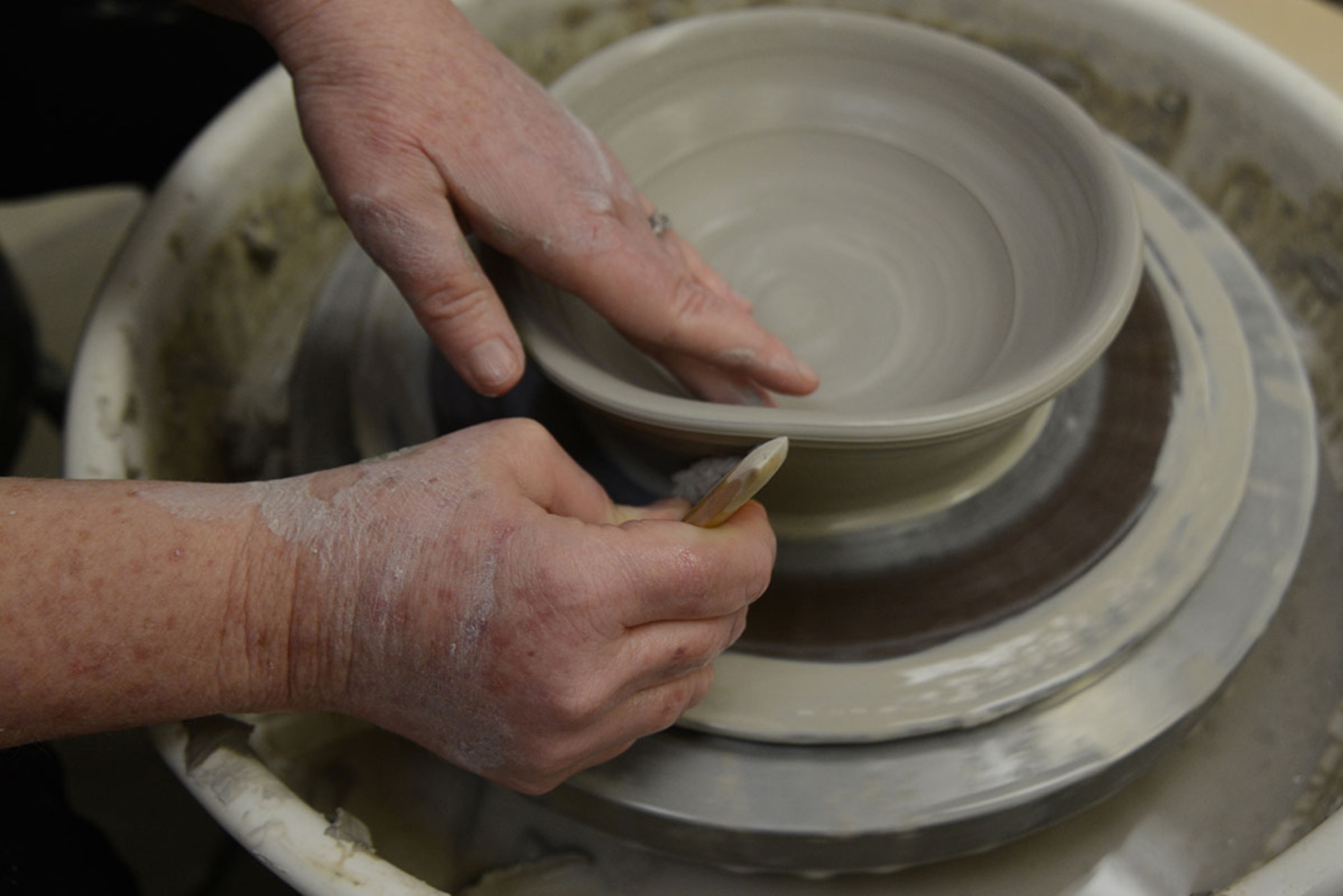 U.S. Coast Guard spouse Laura Fox scrapes the bottom of her bowl with a wood rib on a pottery wheel at the Polar Express Arts and Crafts Center at Joint Base Elmendorf-Richardson, Alaska, Feb. 28, 2016. Fox began creating pottery four years ago, but moved to Alaska seven months ago with her spouse Senior Chief Petty Officer Alan Fox, United States Coast Guard Sector Anchorage command center supervisor. The arts and crafts center allows patrons to use any tools available for their craft like wooden ribs, the pottery wheel and the kiln for an hourly fee. (U.S. Air Force photo by Airman 1st Class Christopher R. Morales)