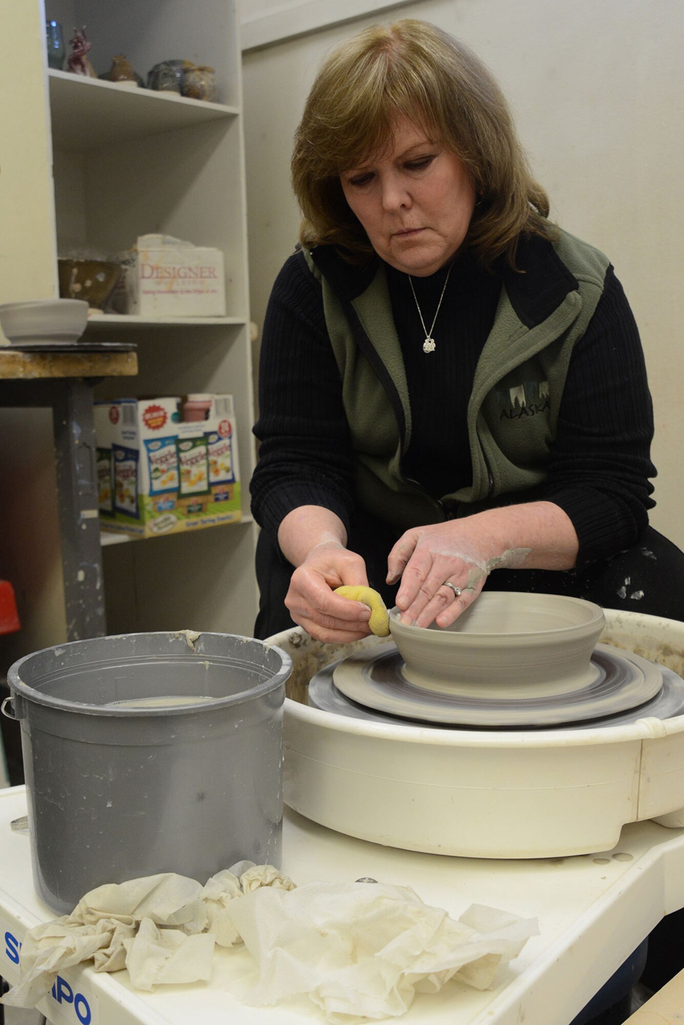 U.S. Coast Guard spouse Laura Fox softens the edges of her bowl with a sponge on a pottery wheel at the Polar Express Arts and Crafts Center at Joint Base Elmendorf-Richardson, Alaska, Feb. 28, 2016. Fox goes to the arts and crafts center twice a week to make bowls, plates, cups and other clay creations. Fox began creating pottery four years ago, but moved to Alaska seven months ago with her spouse Senior Chief Petty Officer Alan Fox, United States Coast Guard Sector Anchorage command center supervisor. (U.S. Air Force photo by Airman 1st Class Christopher R. Morales)