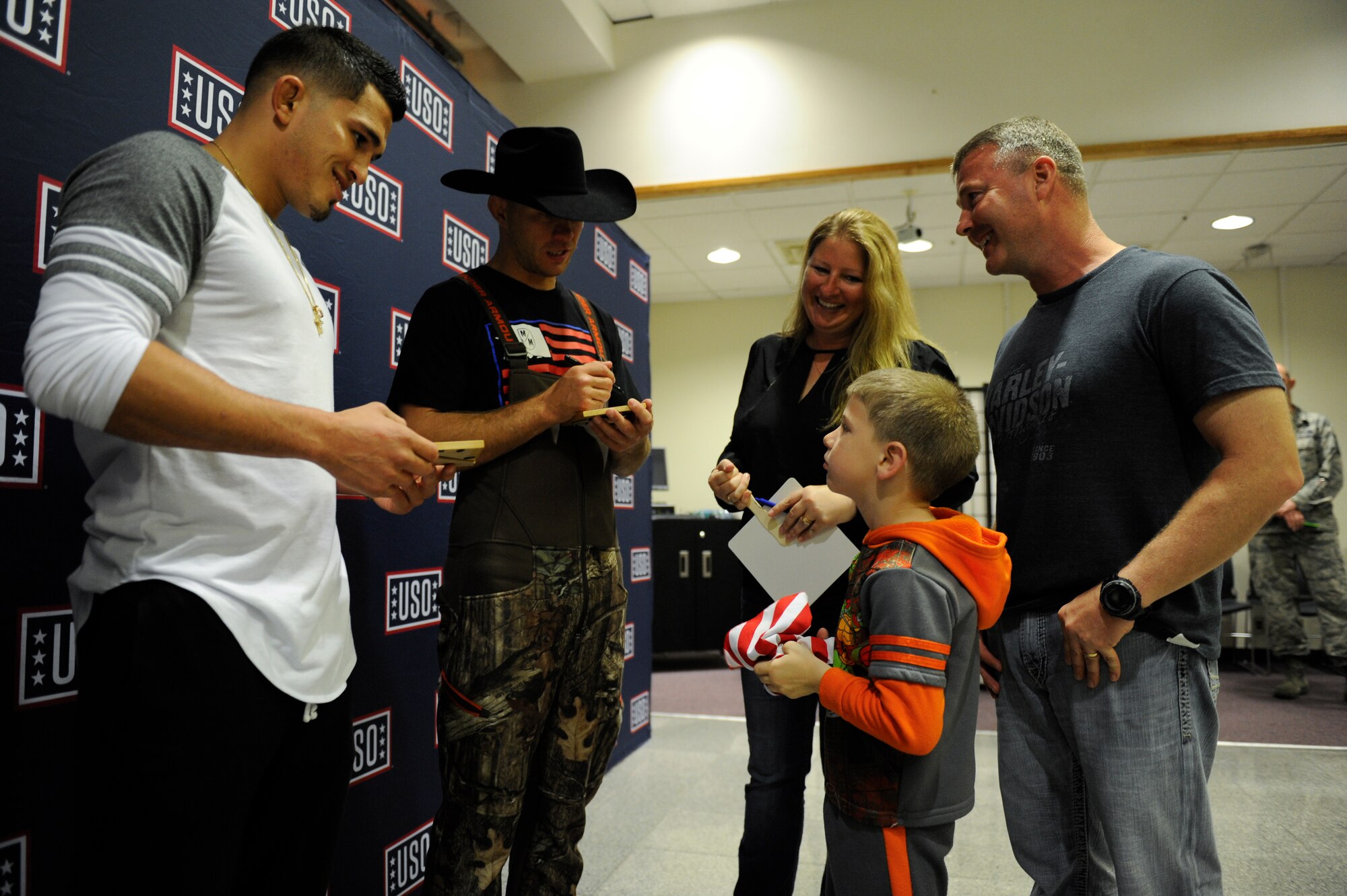 Ultimate Fighting Championship athletes Anthony Pettis and Donald Cerrone sign autographs for a family during a United Service Organizations Spring Visit tour at the Schilling Community Center March 14, 2016, at Kadena Air Base, Japan. Pettis and Cerrone met with Service members and their families as part of the USO's 75th Anniversary celebration to show support for the military. (U.S. Air Force photo by Senior Airman Peter Reft)