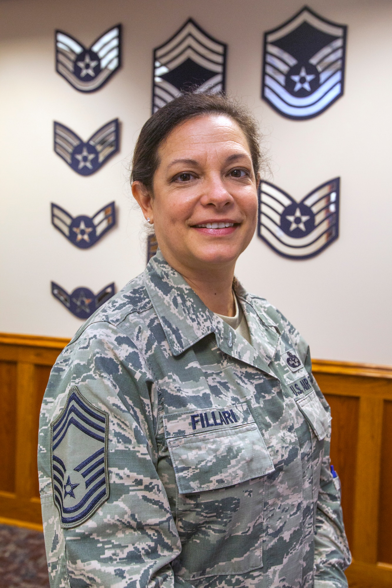 New Jersey State Command Chief Master Master Sgt.  Janeen M. Fillari stands in front of a wall displaying all the enlisted ranks at Joint Force Headquarters, New Jersey Air National Guard, at Joint Base McGuire-Dix-Lakehurst, N.J., March 15, 2016. Fillari is the first woman to serve as the New Jersey State Command Chief Master Sergeant for the New Jersey Air National Guard. (U.S. Air National Guard photo by Master Sgt. Mark C. Olsen/Released)