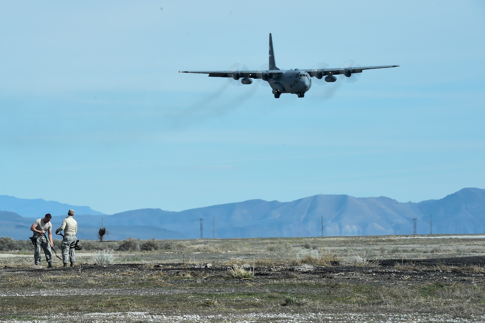 Airmen assigned to the 821st Contingency Response Squadron, build a defense fighting position as a C-130 Hercules aircraft prepares to land during Exercise Turbo Distribution 16-02, March 15, 2016, at Amedee Army Airfield, Calif. Defense fighting positions allow cover and concealment from the enemy and in conjunction with others allows 360 degrees field of fire around the base. (U.S. Air Force photo by Staff Sgt. Robert Hicks/Released)