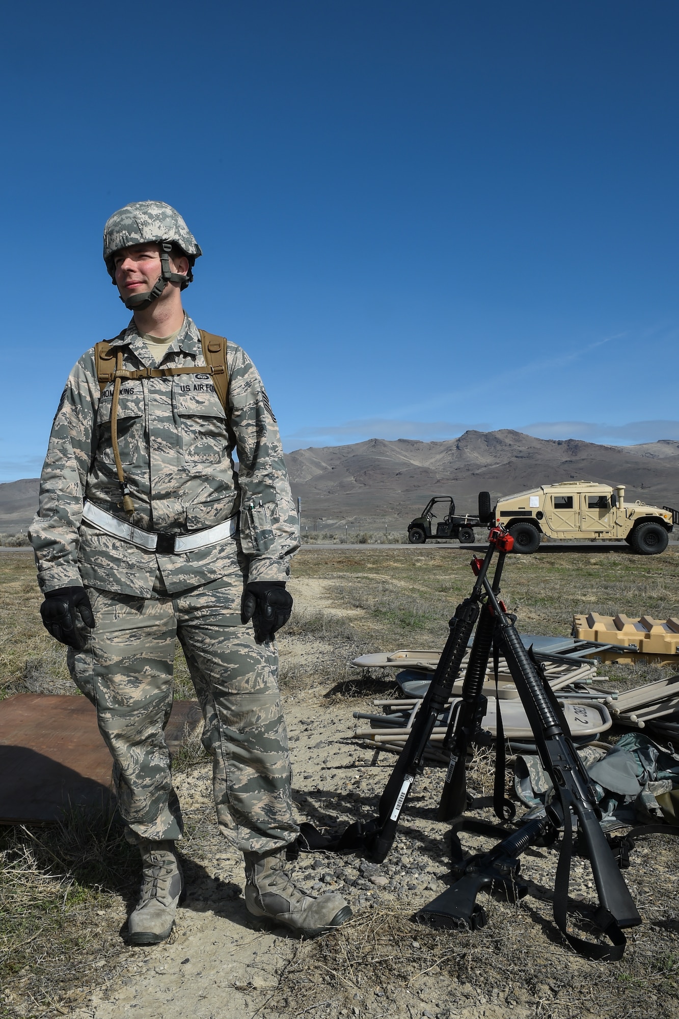 Tech. Sgt. Brian Thompkins, 921st Contingency Response Squadron weather forecaster, guards M16 assault rifles while other Airmen and Soldiers work on putting tents together during Exercise Turbo Distribution 16-02, March 15, 2016, at Amedee Army Airfield, Calif. The service members took turns guarding the weapons throughout the day until the tents were assembled. (U.S. Air Force photo by Staff Sgt. Robert Hicks/Released)