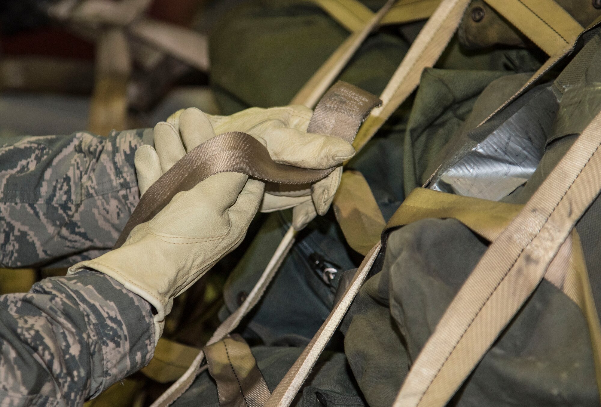 A 35th Logistics Readiness Squadron augmentee tightens straps on cargo at Misawa Air Base, Japan, March 15, 2016. These cargo deployment function personnel are responsible for building, labeling and loading cargo pallets. Pallets hold cargo in place during flights to ensure more stability and safety.  (U.S. Air Force photo by Airman 1st Class Jordyn Fetter)