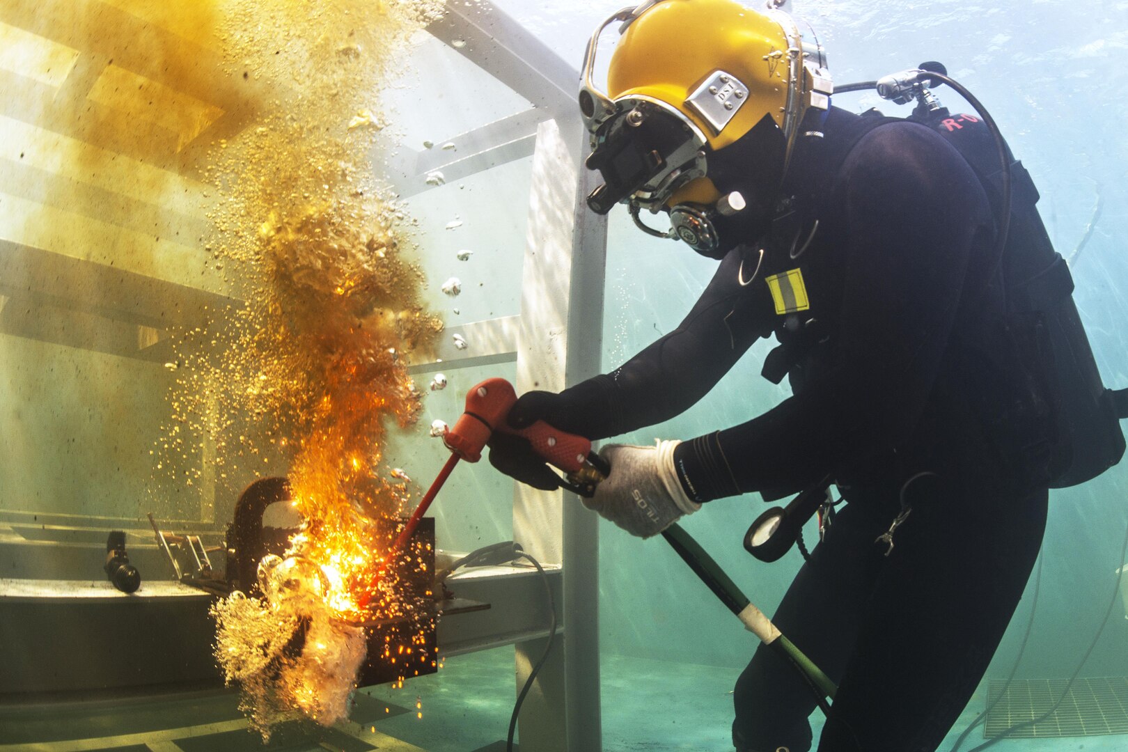 Navy Lt. Christopher Ferguson uses an exothermic torch to cut a steel plate in a training pool at a South Korean engineering school in Jinhae, South Korea, March 17, 2016, during Exercise Foal Eagle 2016. Ferguson is a dive medical officer. Navy photo by Petty Officer 1st Class Charles E. White