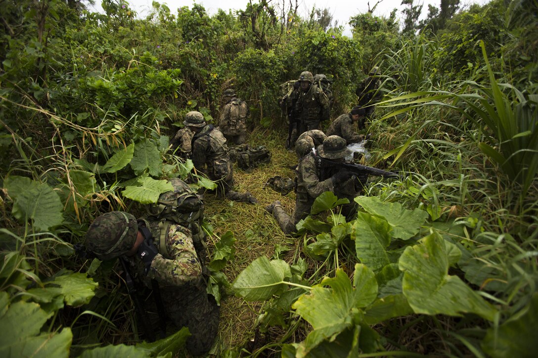 Japan Ground Self-Defense Force members prepare to patrol towards their mission objective Mar. 11, at Kin Blue, Okinawa, Japan. Upon landing on the beach, the JGSDF members changed out of their wet clothes in order to patrol through the jungle. The JGSDF observed U.S. Marines with 3rd Reconnaissance Battalion, 3rd Marine Division, III Marine Expeditionary Force, conducting raid missions, amphibious training and scout swimmer classes. The JGSDF members are with the 43rd Infantry Regiment, 8th Division, Western Army. (U.S. Marine Corps photo by Cpl. Isaac Ibarra/Released)