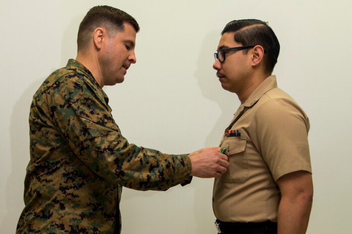 Col. Robert V. Boucher, left, commanding officer of Marine Corps Air Station Iwakuni, pins the Navy and Marine Corps Achievement Medal on Petty Officer 3rd Class Jason Aguirre, a logistics specialist with Headquarters and Headquarters Squadron, after Aguirre was awarded with Marine Corps Installations Pacific Junior Sailor of the Year at MCAS Iwakuni, Japan, March 10, 2016. Aguirre said becoming Sailor of the Year wasn’t an easy task and participating in Marine Corps activities helped him achieve his newly appointed title. Aguirre said he is grateful for the award and plans to keep on bettering himself. (U.S. Marine Corps photo by Lance Cpl. Aaron Henson/Released)