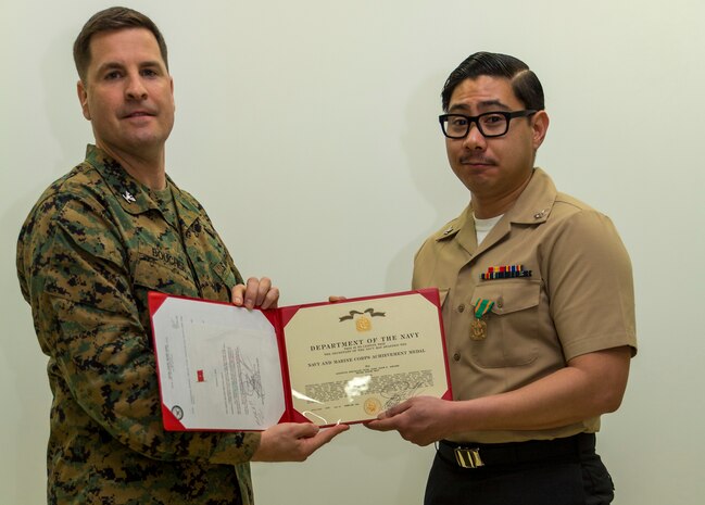 Petty Officer 3rd Class Jason Aguirre, right, a logistics specialist with Headquarters and Headquarters Squadron, poses for a photo with Col. Robert V. Boucher, commanding officer of Marine Corps Air Station Iwakuni, after being awarded the Marine Corps Installations Pacific Junior Sailor of the Year at MCAS Iwakuni, Japan, March 10, 2016. Aguirre said becoming sailor of the year wasn’t an easy task and participating in Marine Corps activities helped him achieve his newly appointed title. (U.S. Marine Corps photo by Lance Cpl. Aaron Henson/Released)