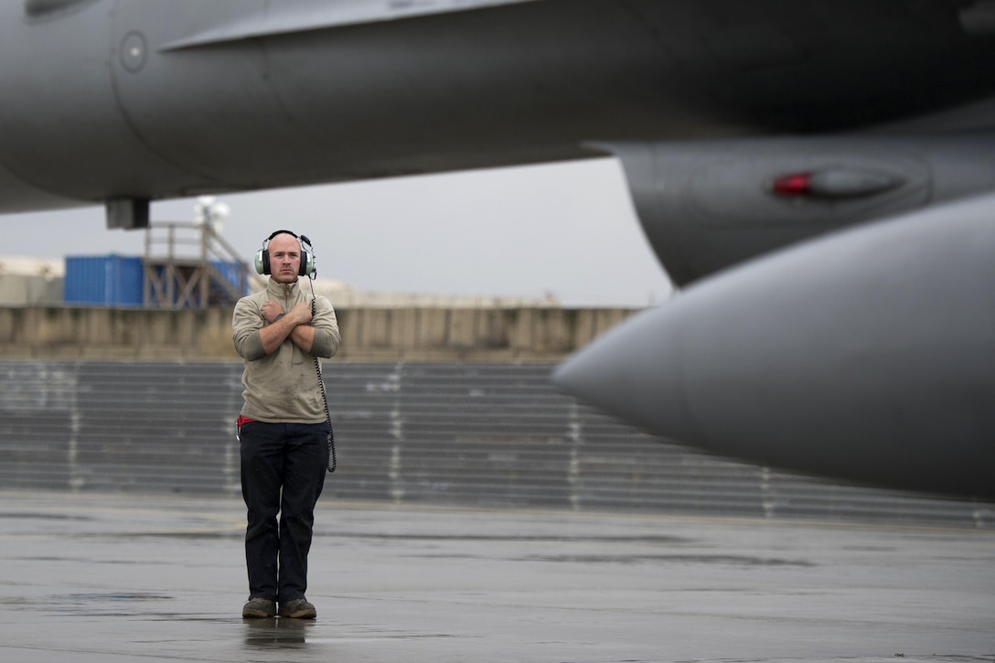 Air Force Staff Sgt. Jacob Heaton holds an F-16 Fighting Falcon aircraft on the ramp on Bagram Airfield, Afghanistan, March 14, 2016, before a combat sortie. Heaton is a crew chief assigned to the 455th Expeditionary Aircraft Maintenance Squadron. Air Force photo by Tech. Sgt. Robert Cloys