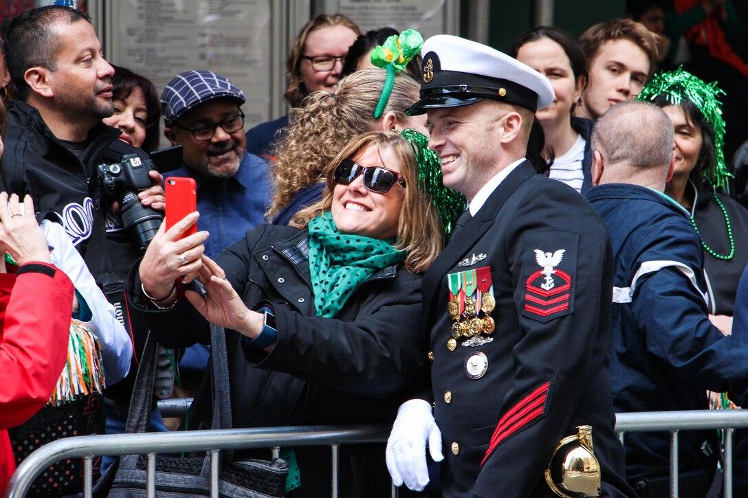 Navy Chief Petty Officer Adam Chubbuck poses for a selfie with a crowd member during the 255th St. Patrick's Day Parade in New York City, March 17, 2016. Chubbuck is a Navy counselor with the U.S. Navy Ceremonial Guard. Navy photo by Lt. Matthew Stroup