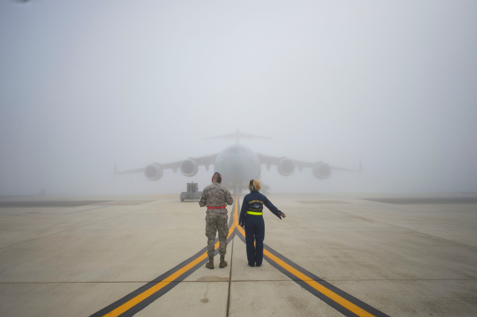 Tech. Sgt. Christine King (right), 512th Airlift Wing, shows Airman 1st Class Anthony Mahon, 436th Airlift Wing, the different signaling procedures to safely marshal a C-17 Globemaster III aircraft on Dover Air Force Base, Del., March 17, 2016. King regularly trains younger and less experienced active-duty and reserve Airmen in the C-17 maintenance career field. (U.S. Air Force photo/ Capt. Bernie Kale)
