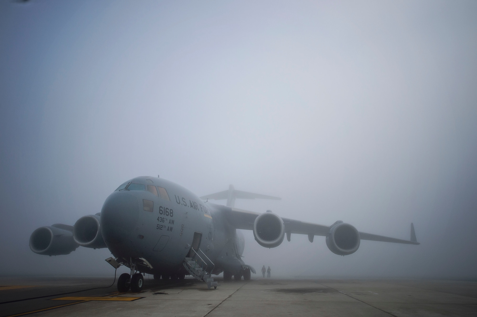 On a foggy flightline, Tech. Sgt. Christine King (right), 512th Airlift Wing, and Airman 1st Class Anthony Mahon, 436th Airlift Wing, walk to the rear of a Team Dover C-17 Globemaster III to train on aircraft marshalling procedures on Dover Air Force Base, Del., March 17, 2016. Experienced reservists from the 512th Airlift Wing frequently train active-duty Airmen in various career field tasks. (U.S. Air Force photo/ Capt. Bernie Kale)