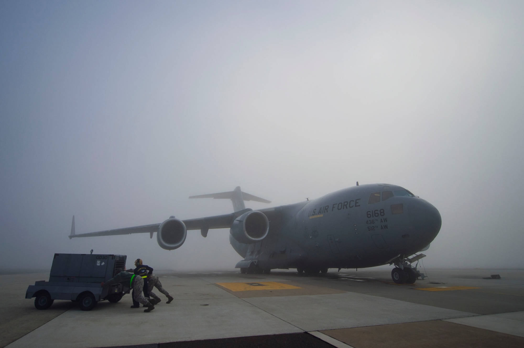 Tech. Sgt. Christine King (middle), 512th Airlift Wing, helps active-duty Airmen push an aircraft generator out of the way in foggy conditions prior to the C-17 Globemaster III aircraft launch on Dover Air Force Base, Del., March 17, 2016. Reservists and active-duty Airmen work side-by-side daily in maintenance and other career fields, fostering Total Force Integration within Team Dover. (U.S. Air Force photo/ Capt. Bernie Kale)