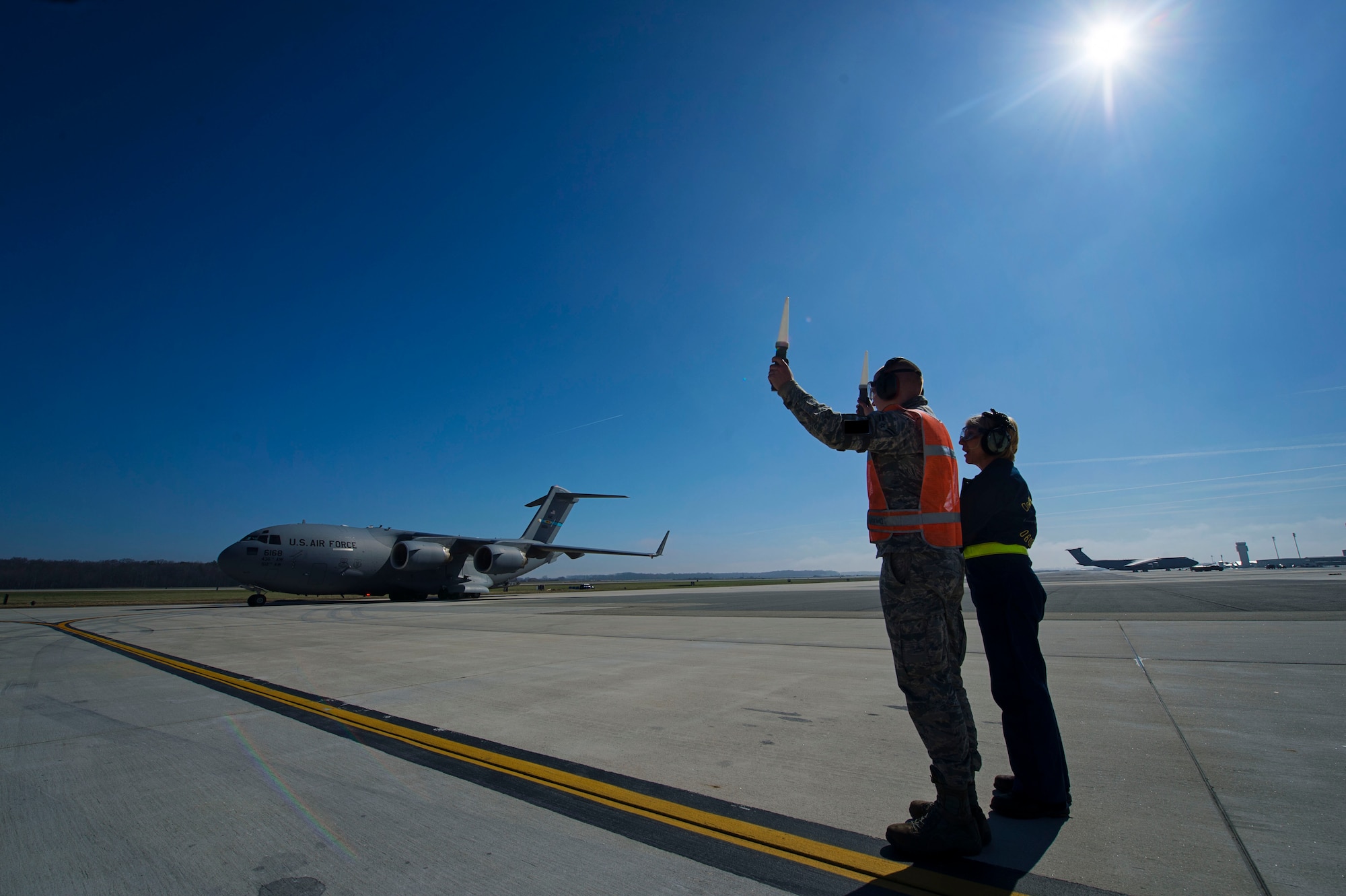 Tech. Sgt. Christine King (right), 512th Airlift Wing, explains to Airman 1st Class Anthony Mahon, 436th Airlift Wing, on safely marshalling a C-17 Globemaster III on the Dover Air Force Base, Del., flightline March 17, 2016. King frequently train young active duty Airmen and reservists who may need training in certain career fields. (U.S. Air Force photo/ Capt. Bernie Kale)