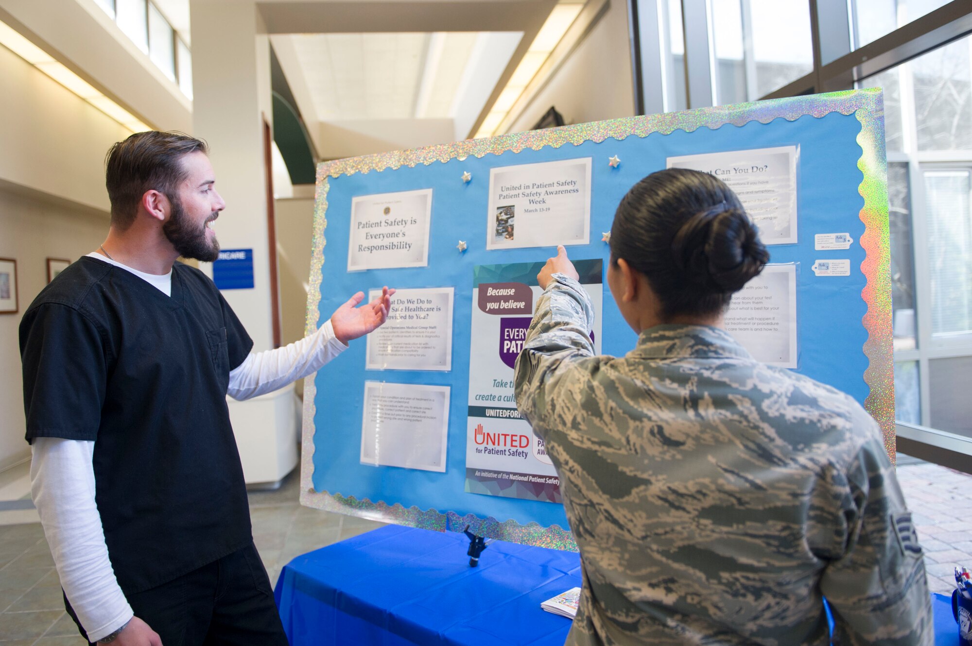 Staff Sgt. Faith De Castro, right, family health administration technician with the 1st Special Operations Medical Group, and Mike Shea, a License Practical Nurse with the 1st SOMDG, discuss information displayed on a patient safety board at Hurlburt Field, Fla., March 16, 2016. The 1st SOMDG recognized National Patient Safety Awareness Week March 13-19.  (U.S. Air Force photo by Senior Airman Krystal M. Garrett)