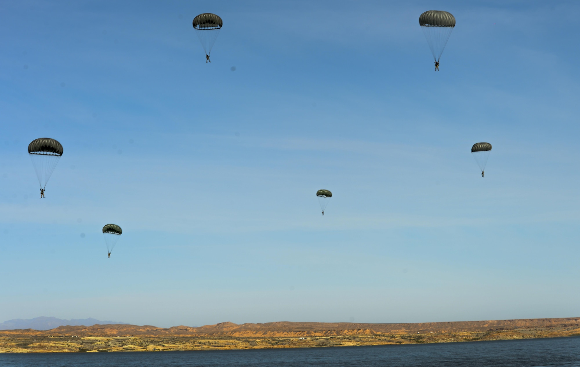 Pararescuemen assigned to the 58th Rescue Squadron at Nellis Air Force Base, Nevada, prepare to land on Lake Mead after preforming static line jumps March 15, 2016. All PJs are qualified experts in Advanced Weapons and Small Unit Tactics, Airborne and Military Free Fall, Combat Divers, High Angle/Confined Space Rescue operations, Small Boat/Vehicle Craft utilization, Rescue Swimmers, and Battlefield Trauma/Paramedics. (U.S. Air Force photo by Airman 1st Class Kevin Tanenbaum)