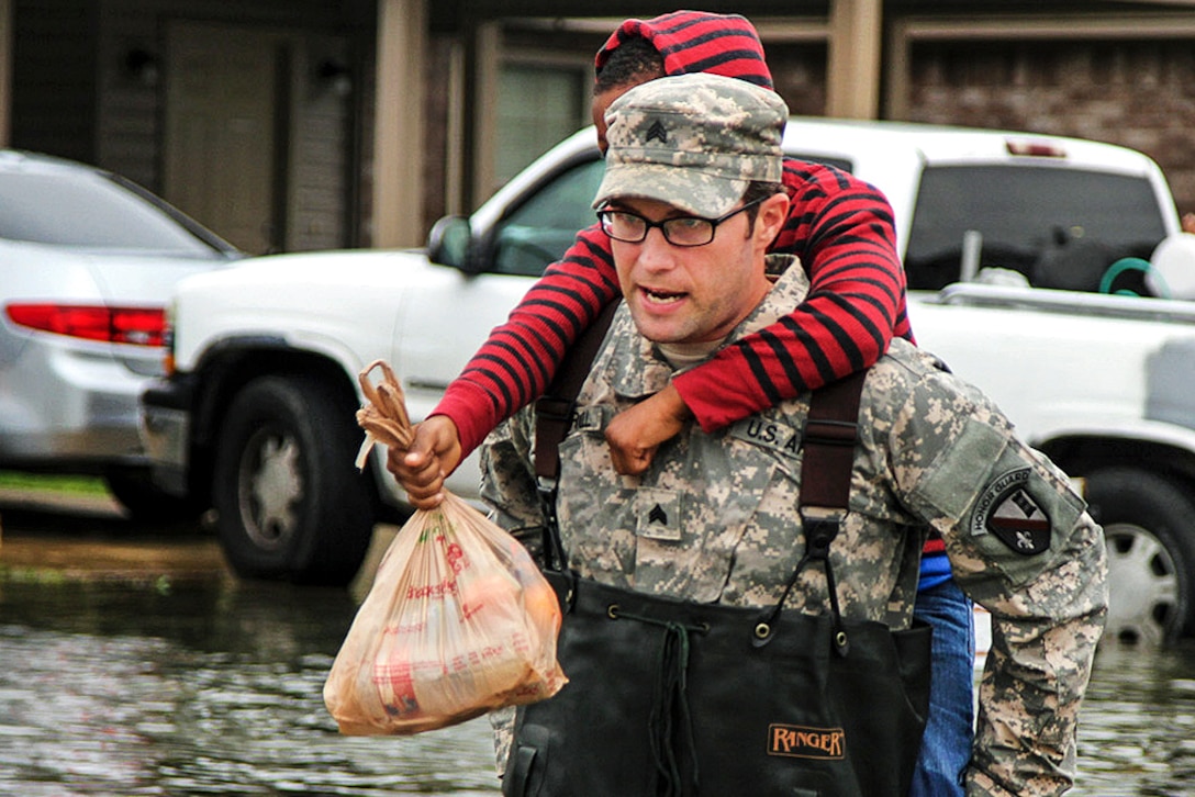 Army Sgt. Jason C. Carroll carries a young resident through flooded streets in Monroe, La., March 10, 2016. Carroll is electronic warfare specialist noncommissioned officer assigned to the Louisiana National Guard's 528th Engineer Battalion, 225th Engineer Brigade. The unit used light tactical vehicles as it worked with the Ouachita Parish Sheriff's Office to navigate the high waters and assist residents. Army National Guard photo by Spc. Tarell J. Bilbo